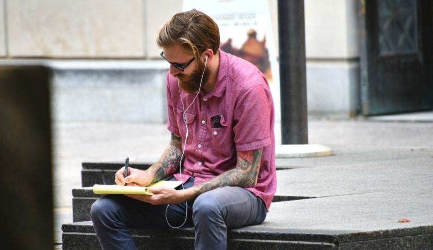 A man writing on a piece of paper while listening to music.