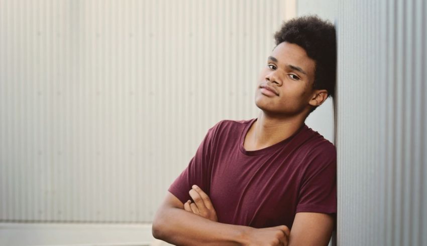 A young black man leaning against a wall.