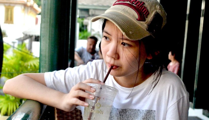 A young woman drinking a drink out of a glass.