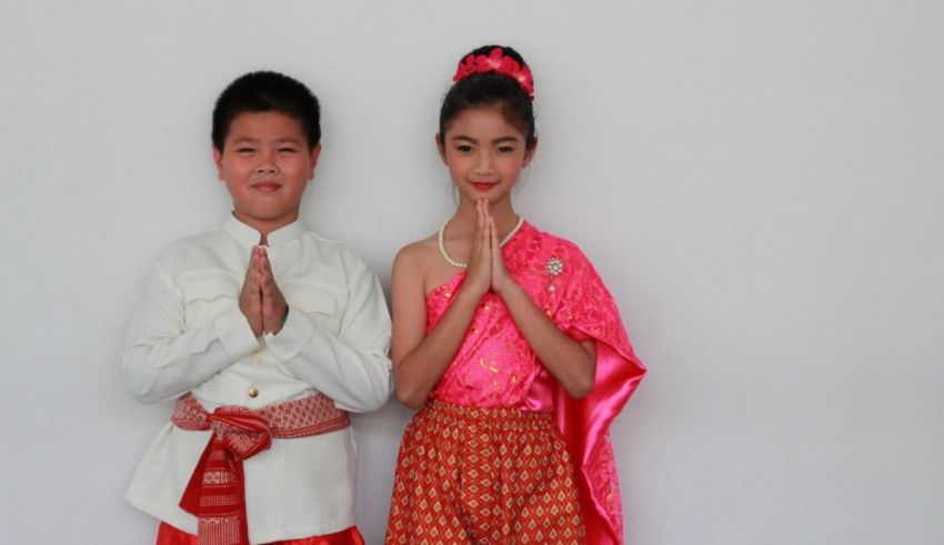 A boy and girl in traditional thai clothing pose for a photo.