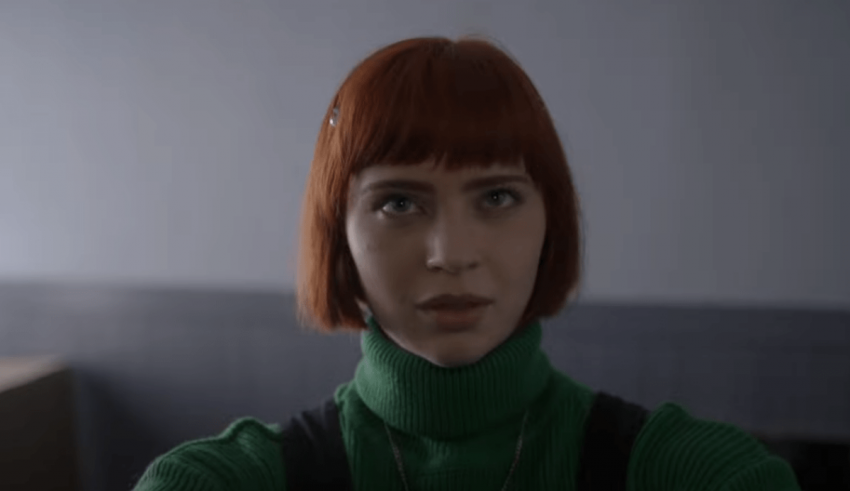 A woman with red hair in a green turtleneck.