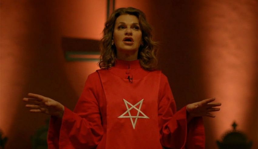 A woman in a red robe holding a pentagram.