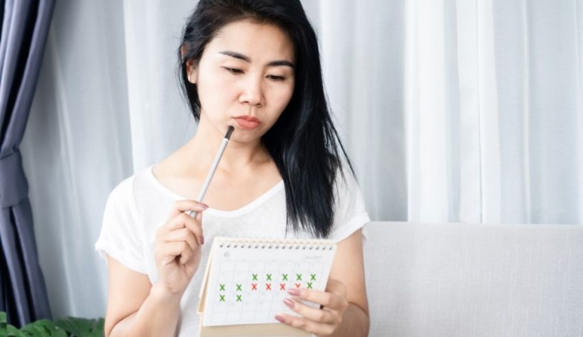 Asian woman looking at a calendar while holding a pen.