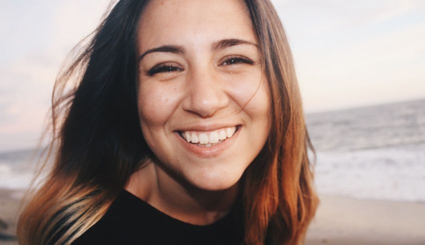 A young woman smiling on the beach.