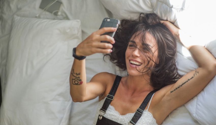 A woman taking a selfie while laying on a bed.