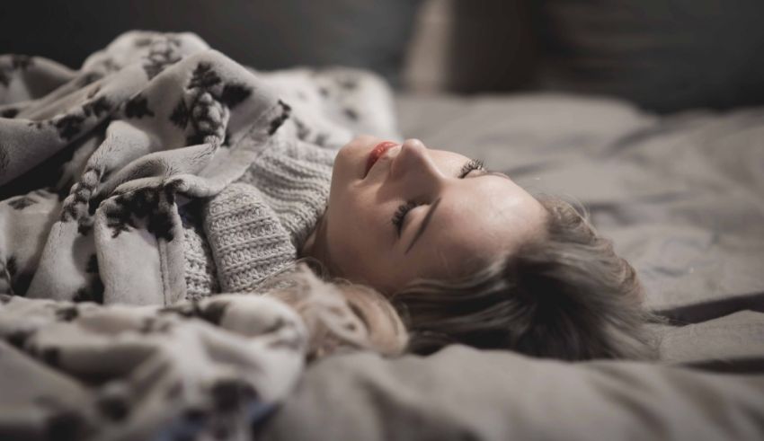 A woman laying in bed with a blanket on her head.