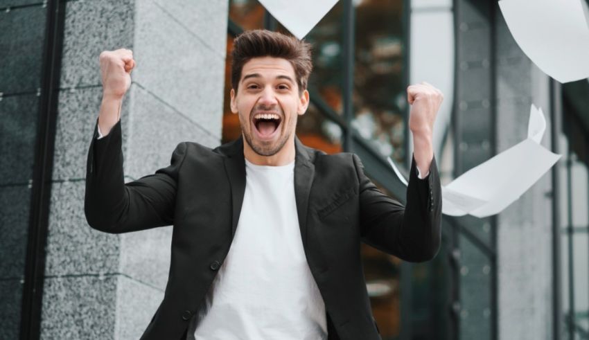 Young businessman celebrating his success in front of a building stock photo.