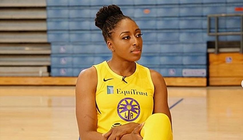 A woman in a yellow uniform sitting on a basketball court.