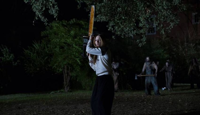 A woman holding a chainsaw in a dark forest.