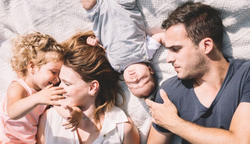 A family laying on a bed with a baby in their arms.