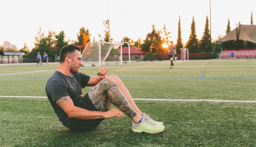 A man sitting on a soccer field at sunset.