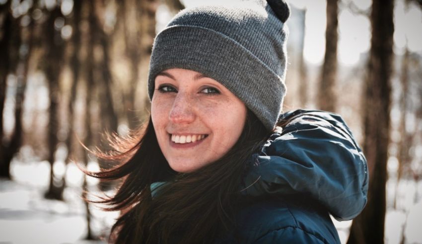 A woman wearing a beanie in the woods.