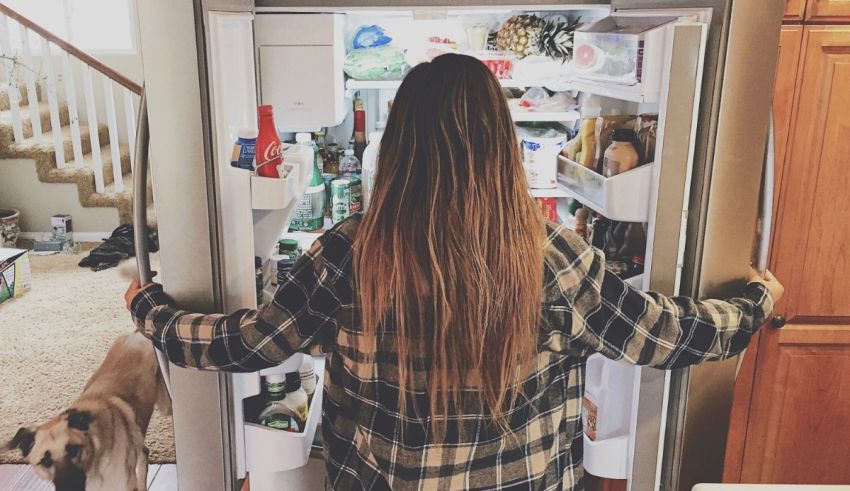 A woman with long hair standing in front of an open refrigerator.