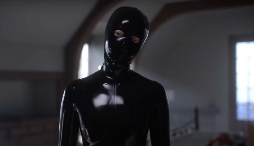 A man in a latex suit is standing in a room.