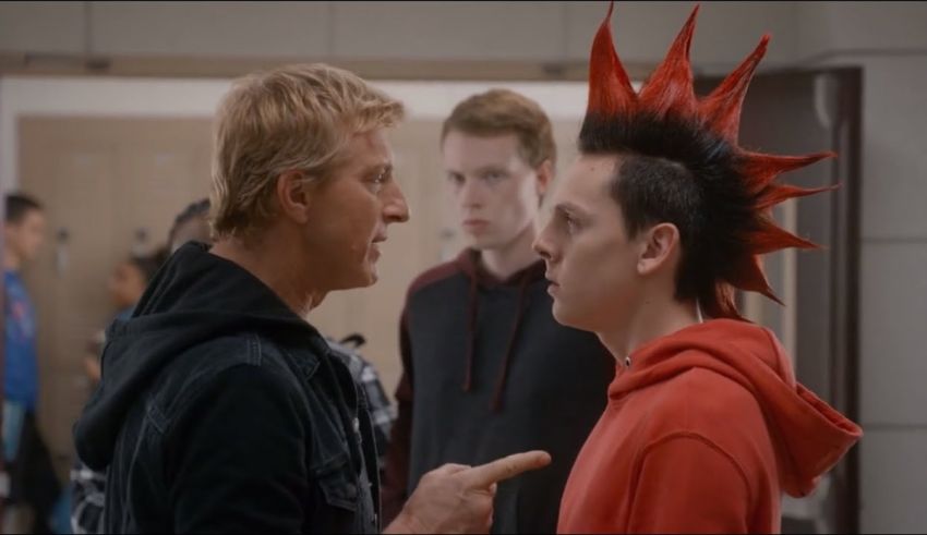 A man with a red mohawk talking to another man in a hallway.