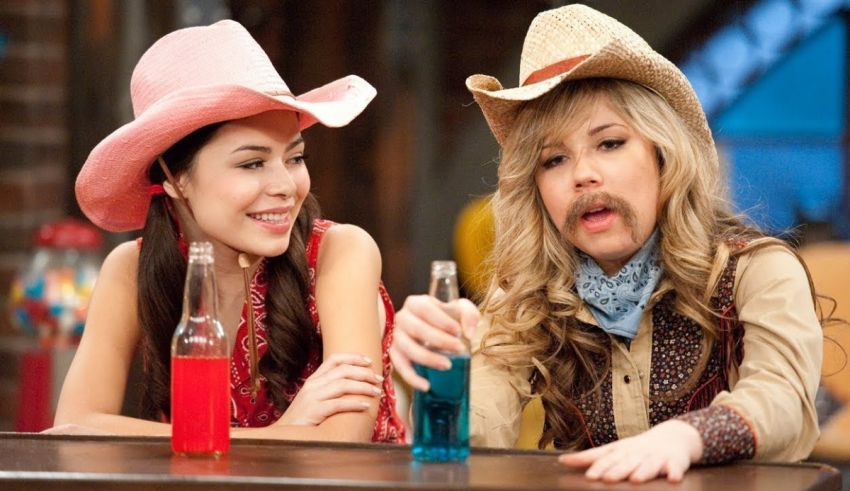 Two girls in cowboy hats are sitting at a bar.