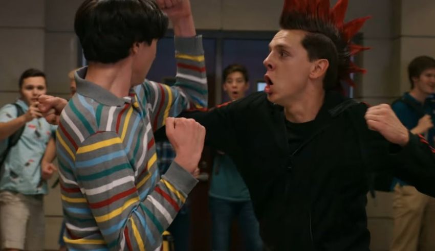 Two young men fighting in front of a group of people.