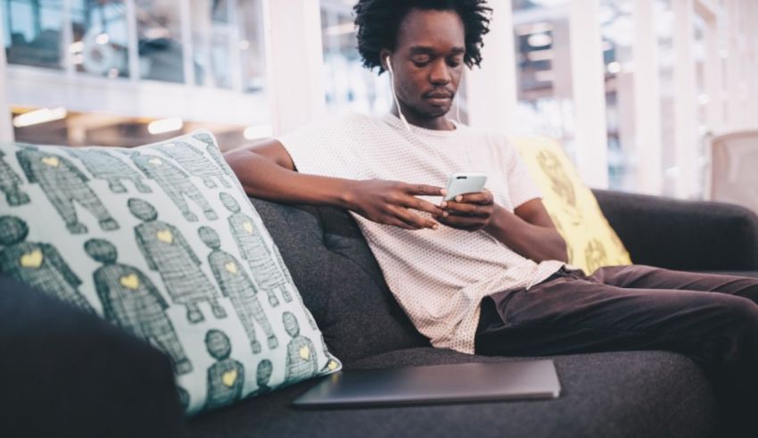 A man sitting on a couch using his phone.
