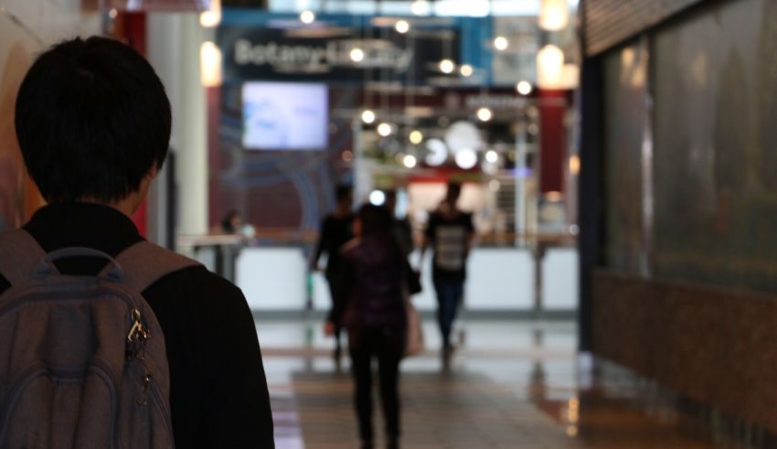 A man with a backpack walking down a mall.