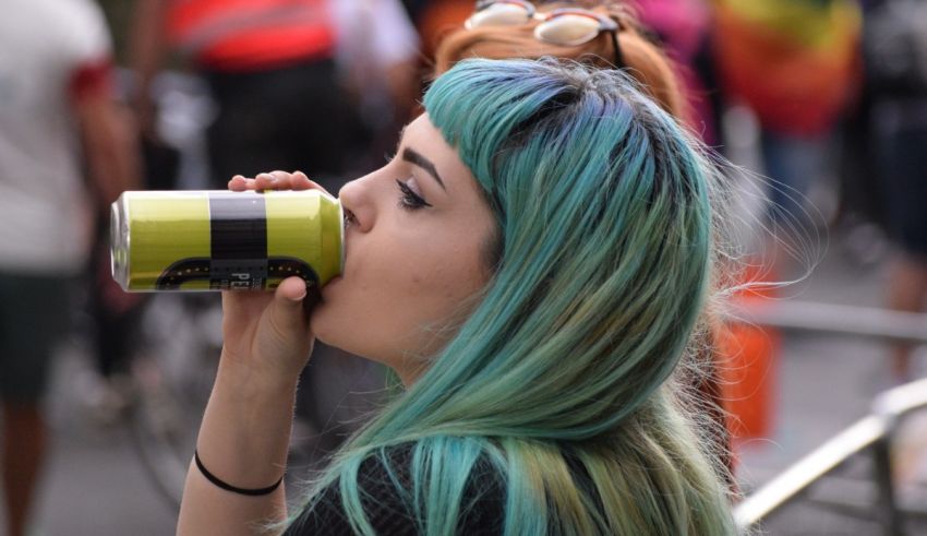 A woman with blue hair drinking from a can.