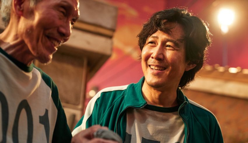 Two men in green t - shirts smiling at each other.