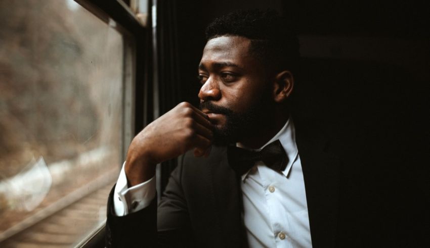 A black man sitting on a train looking out the window.