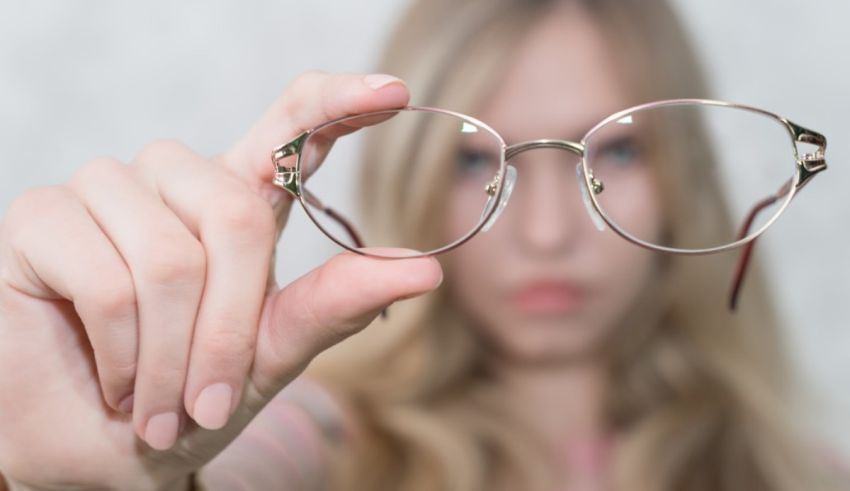 A woman is holding up a pair of glasses.