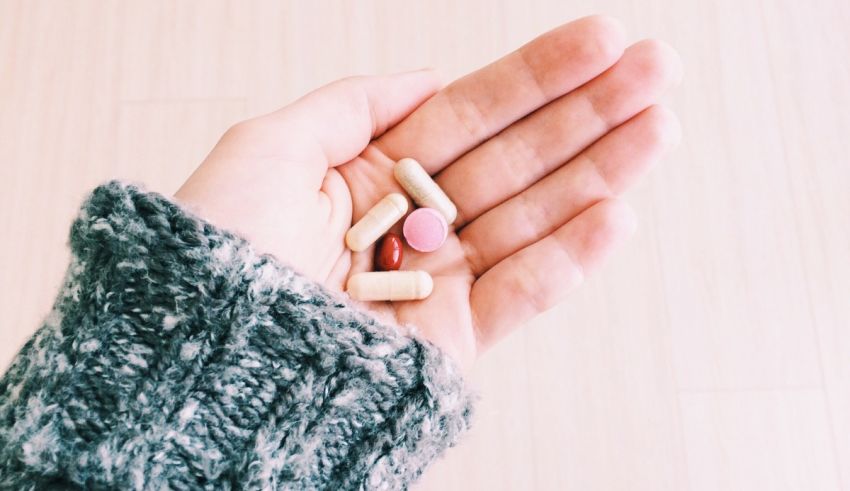 A woman's hand holding a bunch of pills.