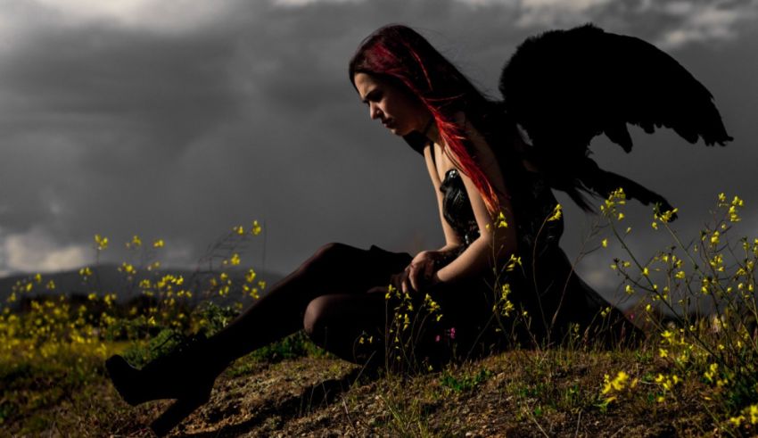 A girl with red hair sitting on a field with flowers.