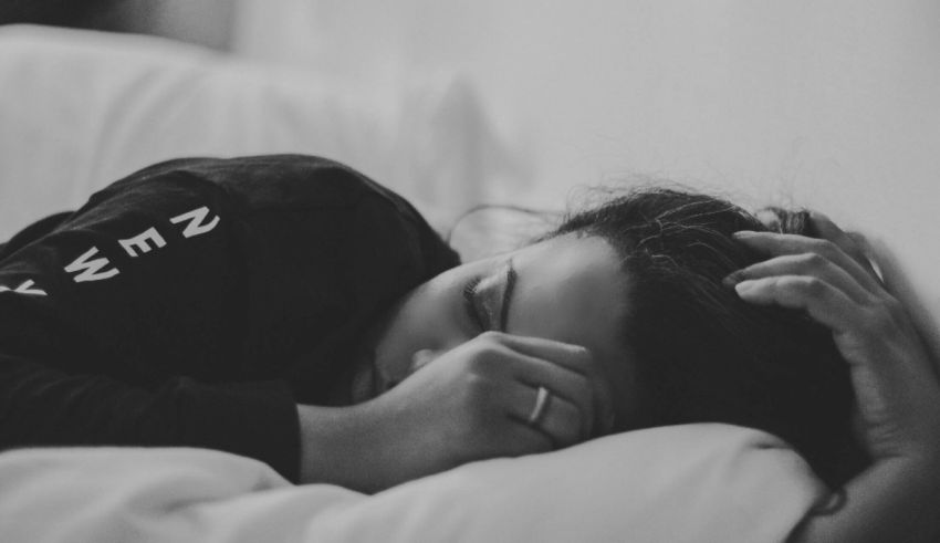 A black and white photo of a woman sleeping in bed.