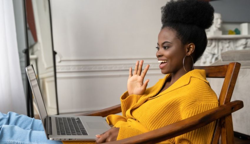 A young black woman sitting in a chair and using a laptop.