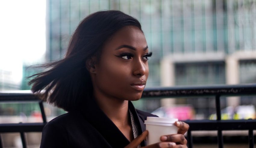 A young black woman holding a cup of coffee.