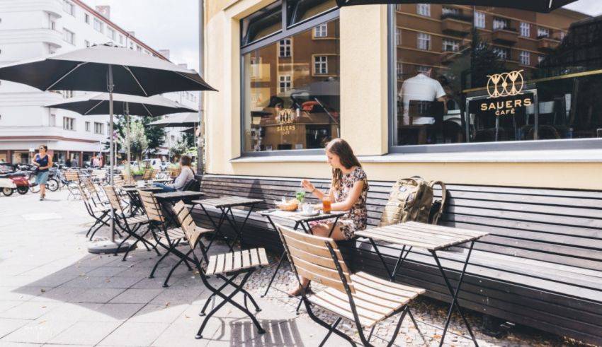 A woman sits at a table outside of a cafe.