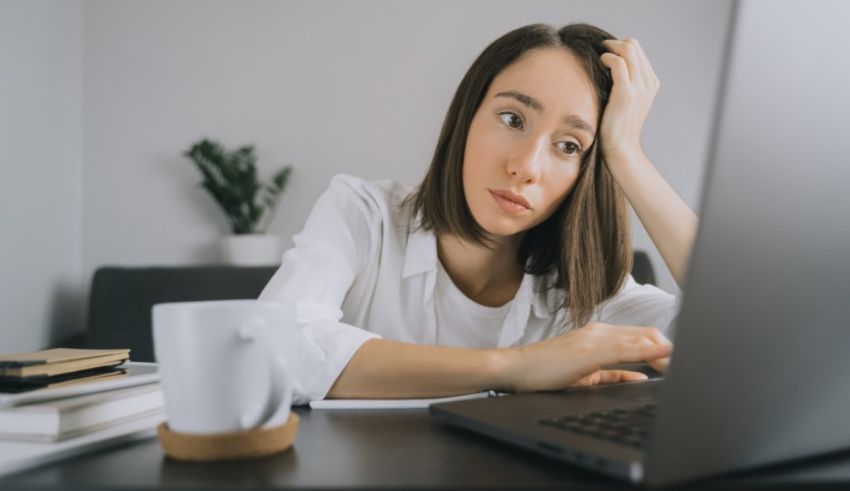 A woman sitting at a desk with a laptop and a cup of coffee.