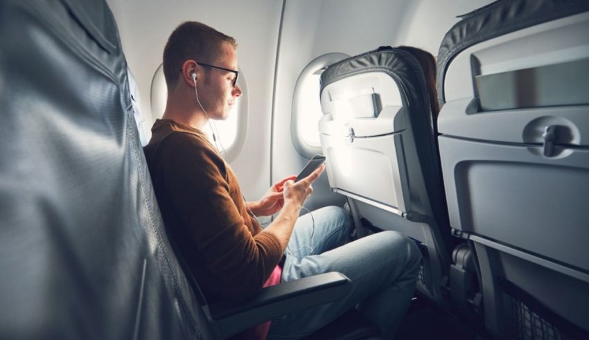 A man sitting on an airplane looking at his phone.