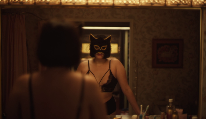 A woman wearing a cat mask in front of a mirror.