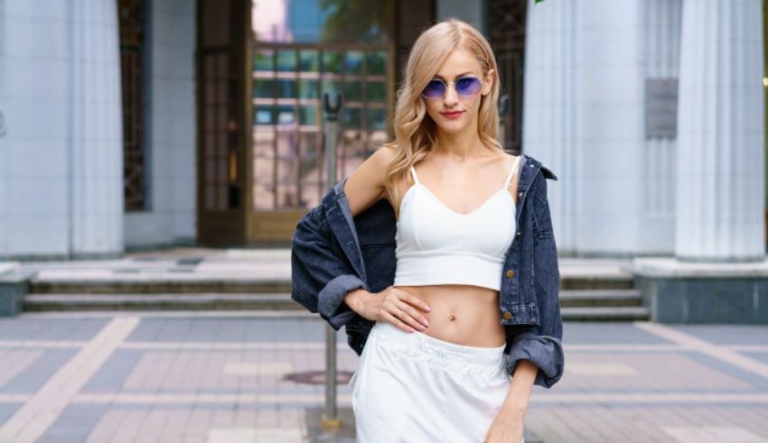 A young woman in white shorts and a denim jacket posing in front of a building.