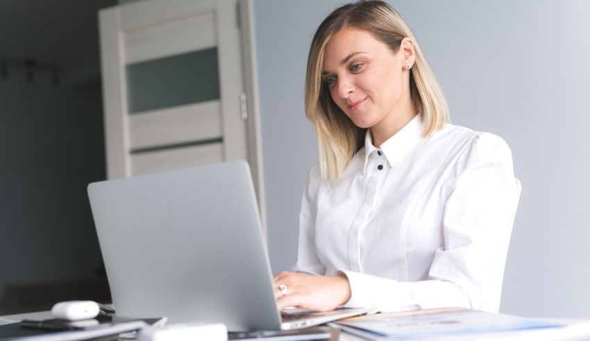 A woman is sitting at a desk using a laptop.