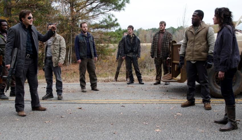 The walking dead cast standing in front of a truck.