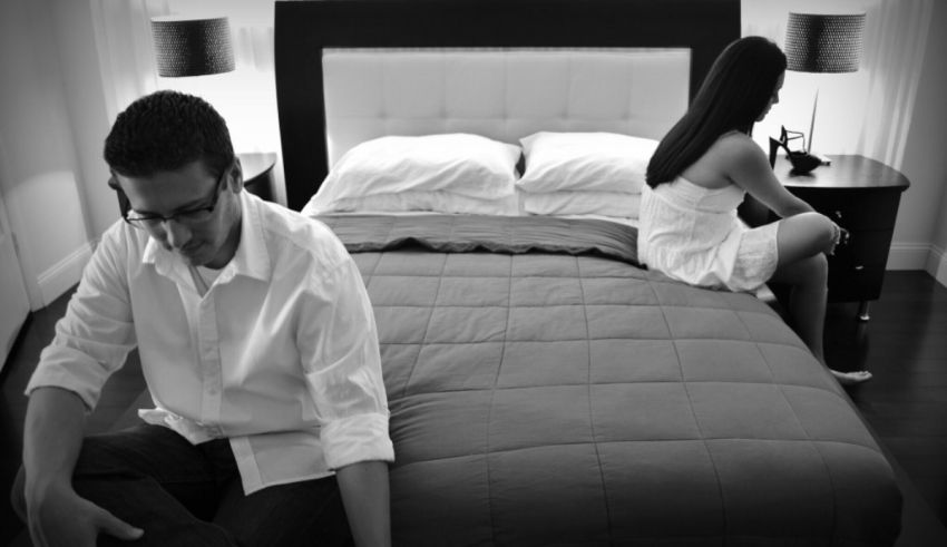 Black and white photo of a man and woman sitting on a bed.