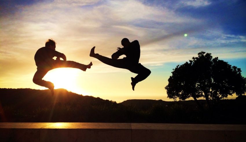 Two people jumping in the air at sunset.