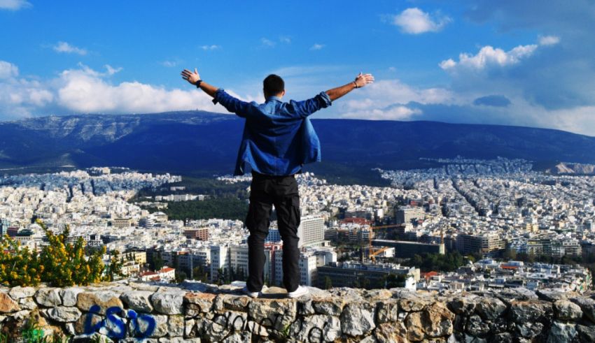 A man standing on a cliff overlooking the city of athens.