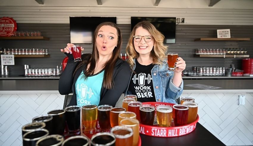 Two women posing in front of a tray of beer.