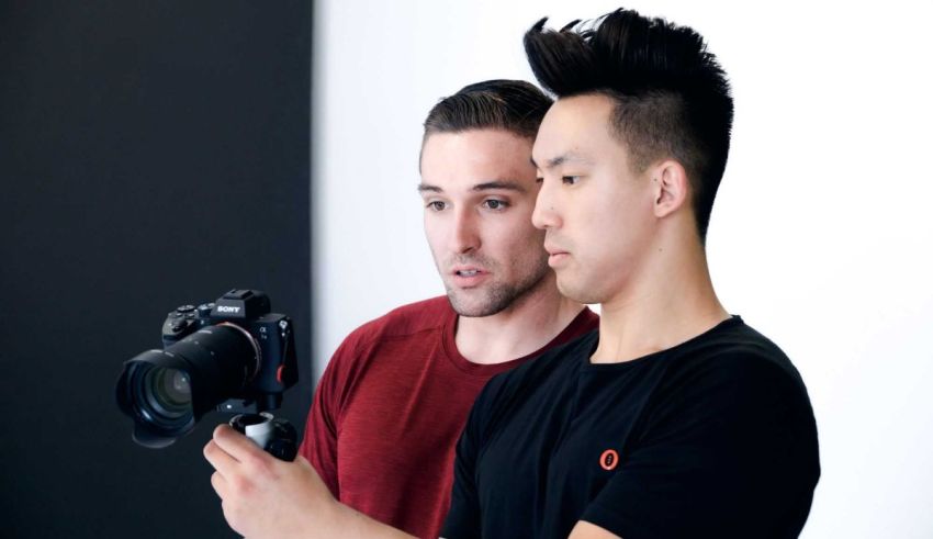 Two men standing next to each other holding a camera.