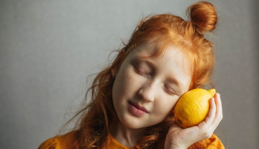 A girl with red hair holding a lemon.