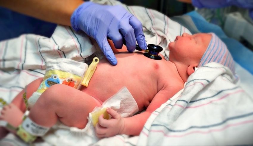 A baby in a hospital bed with a stethoscope.
