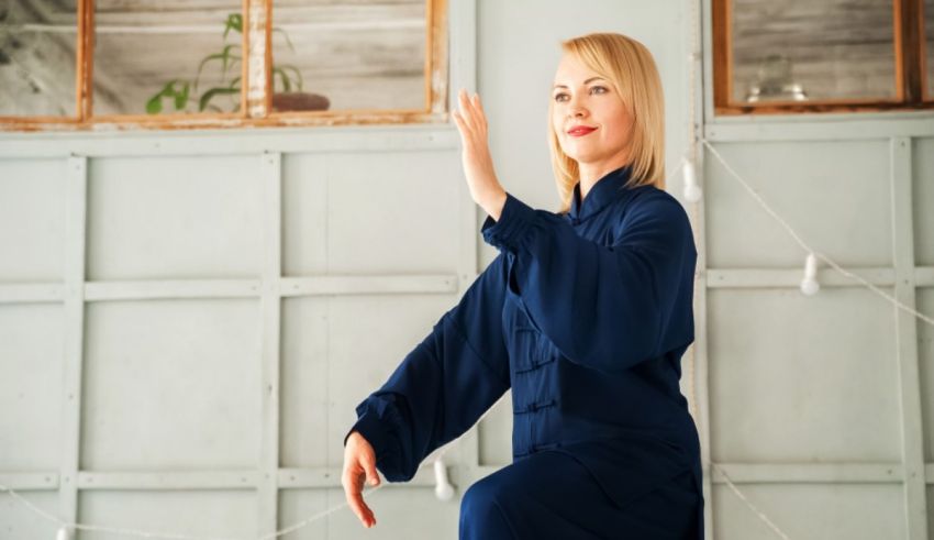 A woman in a blue dress is doing a tai chi exercise.