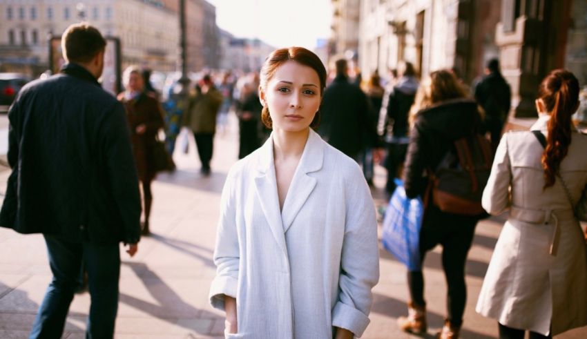 A woman in a white coat standing on a busy street.