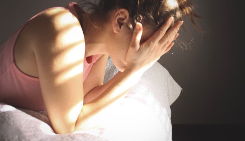 A woman laying on a bed with her hand on her head.