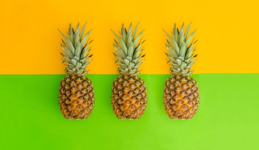 Three pineapples on a yellow and green background.